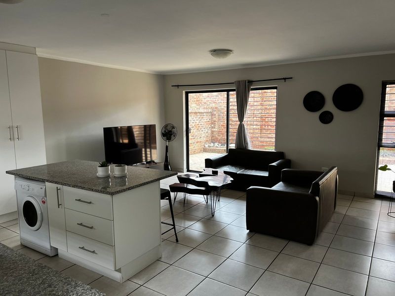 Open-plan living area featuring a kitchen island with granite countertops, tiled flooring, and sliding glass doors leading to a private rear courtyard.