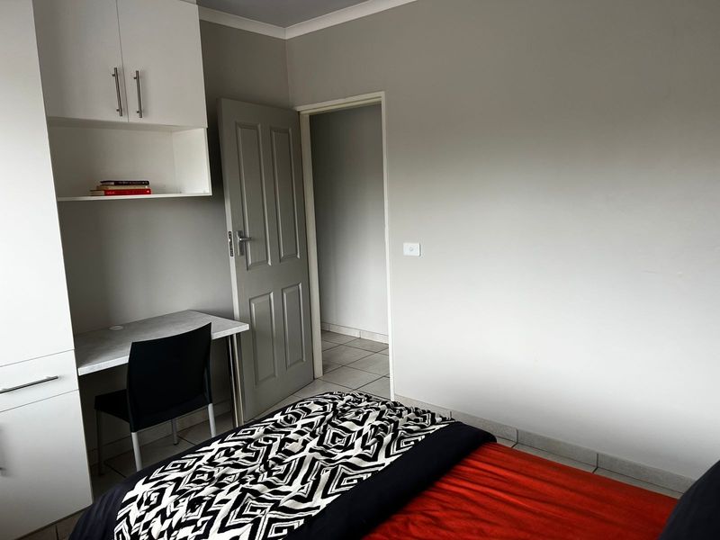 A bedroom featuring built-in cabinetry and a desk area, with neutral wall tones and tiled flooring.