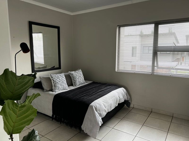 A neutrally painted bedroom featuring tiled flooring and venetian blinds, offering a clean and functional space ready for personalization.