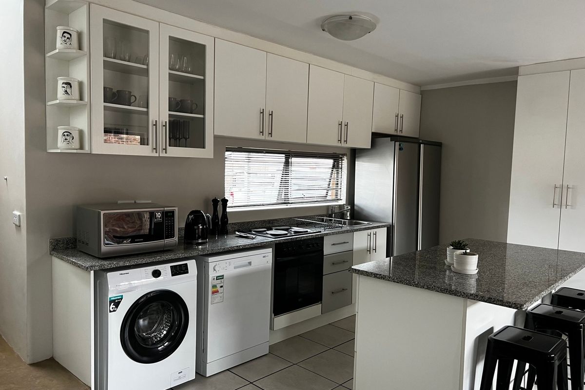 Modern kitchen featuring granite countertops, built-in oven and hob, ample cabinetry, and a functional island, providing a clean and efficient workspace.