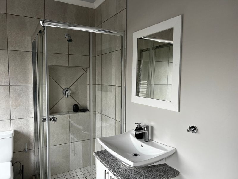 Modern bathroom featuring a glass shower enclosure, built-in shower niche, vanity cabinet with granite countertop, and a contemporary vessel sink.