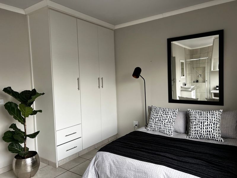 A well-maintained bedroom featuring neutral walls, tiled flooring, and a spacious built-in wardrobe with integrated drawers.