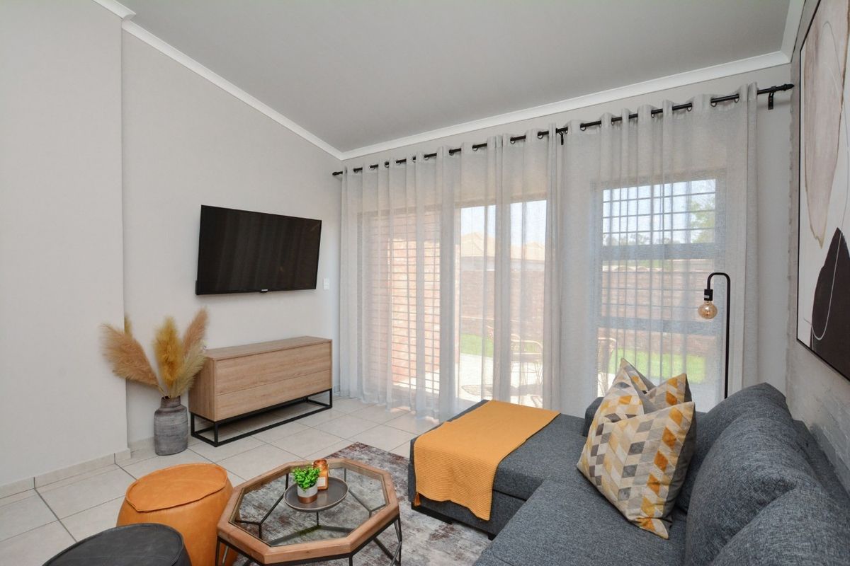 A bright living room featuring tiled flooring, coved ceilings, and large sliding glass doors that provide access to the outdoor area.