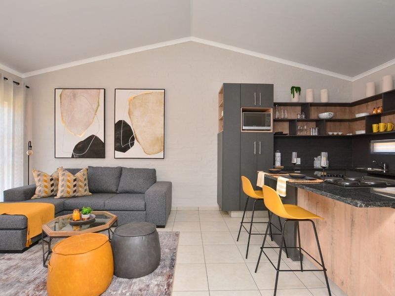 Modern open-plan living area featuring a contemporary kitchen with granite countertops, built-in appliances, and a spacious lounge area with vaulted ceilings.