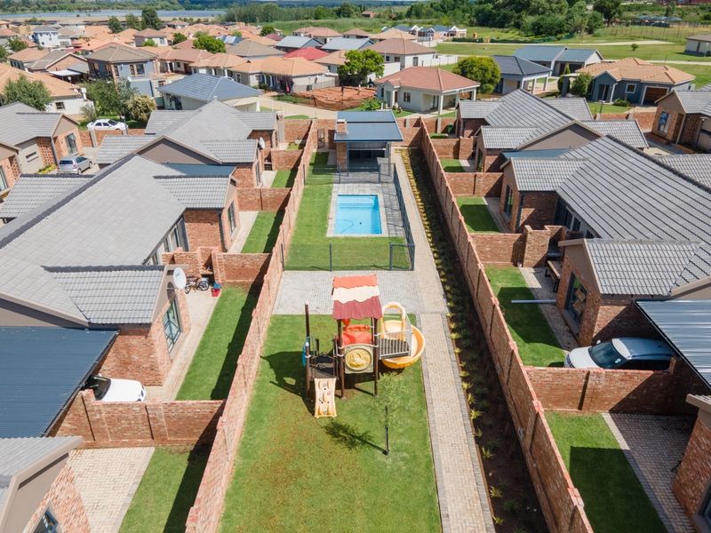 Aerial view of a residential townhouse complex featuring individual brick units, private gardens, paved pathways, and a communal swimming pool area.