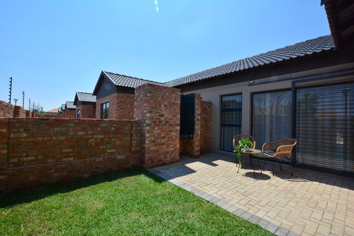 A private rear patio area featuring brick walling, paved flooring, and sliding door access to the townhouse interior.