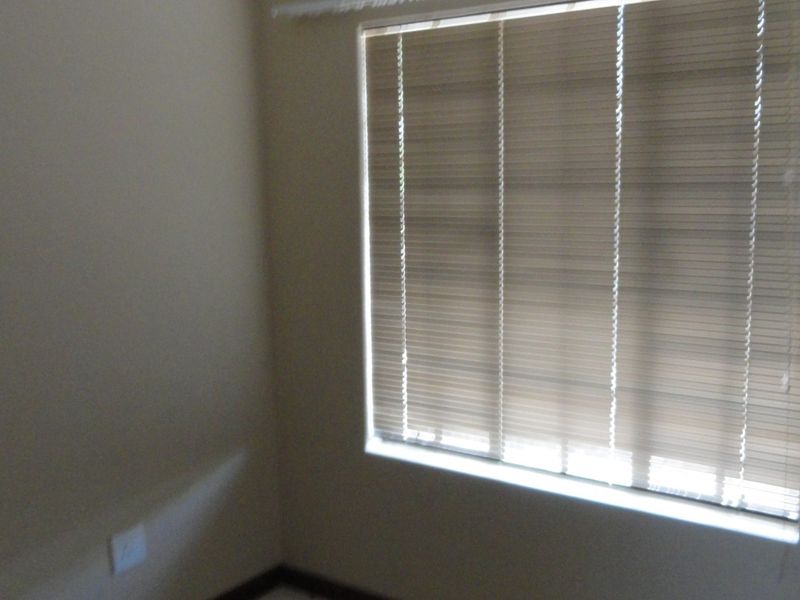 A vacant bedroom featuring neutral walls and fitted venetian blinds, providing a clean and versatile space ready for personalization.