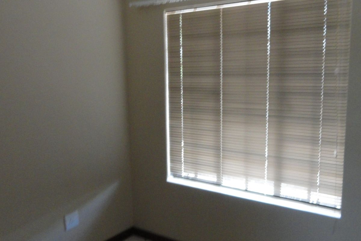 A vacant bedroom featuring neutral walls and fitted venetian blinds, providing a clean and versatile space ready for personalization.