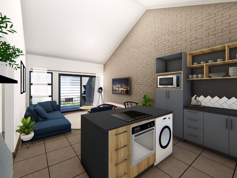 Modern open-plan living area featuring a vaulted ceiling, exposed brick wall, and a contemporary kitchen island with integrated appliances and tiled flooring.