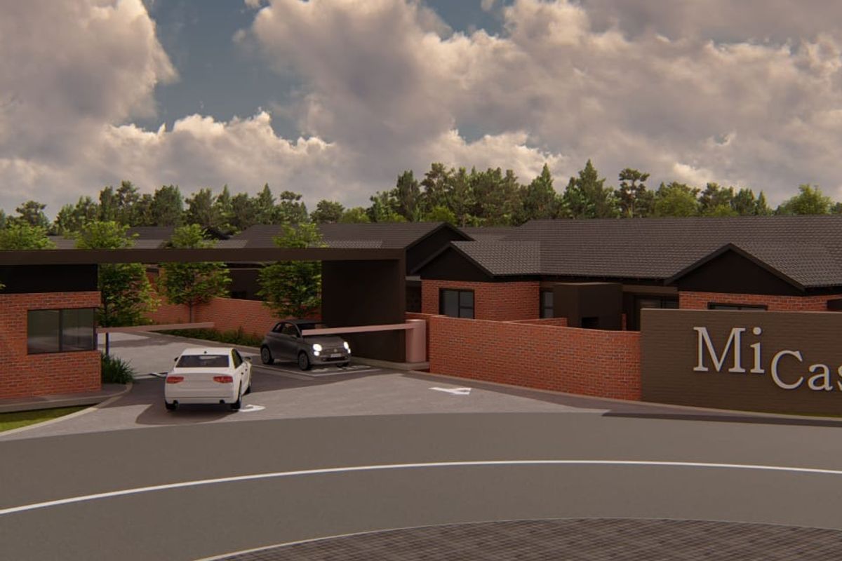 A modern residential complex entrance featuring a secure gated access point, brick boundary walls, and professional signage.