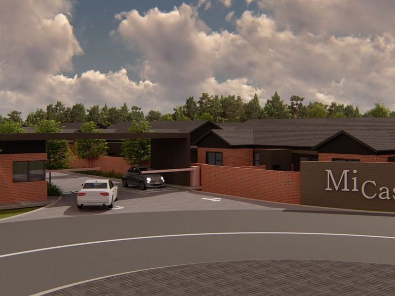A modern residential complex entrance featuring a secure gated access point, brick boundary walls, and professional signage.