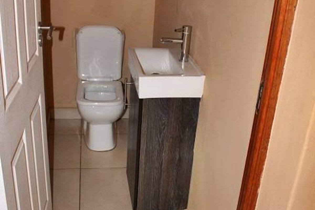 A compact guest bathroom featuring a modern vanity with basin and a standard toilet, finished with tiled flooring.
