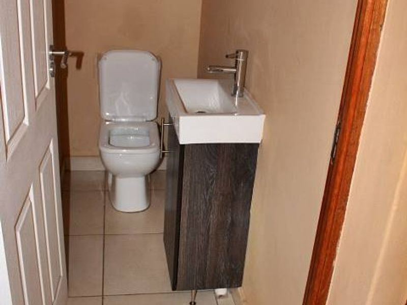 A compact guest bathroom featuring a modern vanity with basin and a standard toilet, finished with tiled flooring.