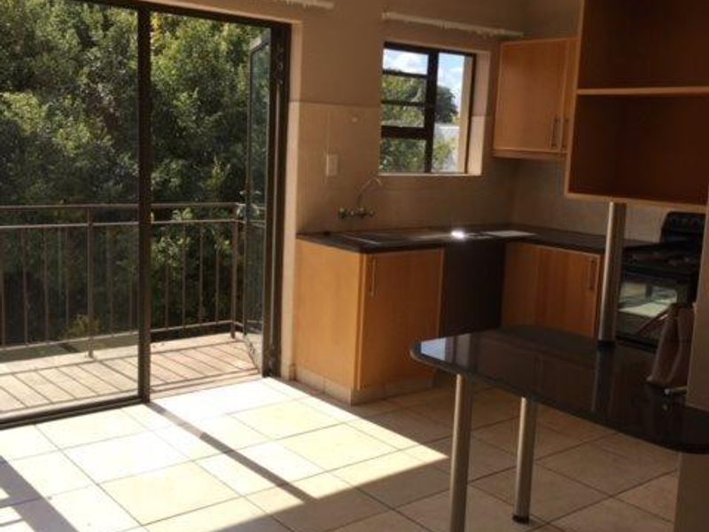 Open plan kitchen and living area featuring tiled floors, built-in cabinetry with granite countertops, and direct access to a private balcony.