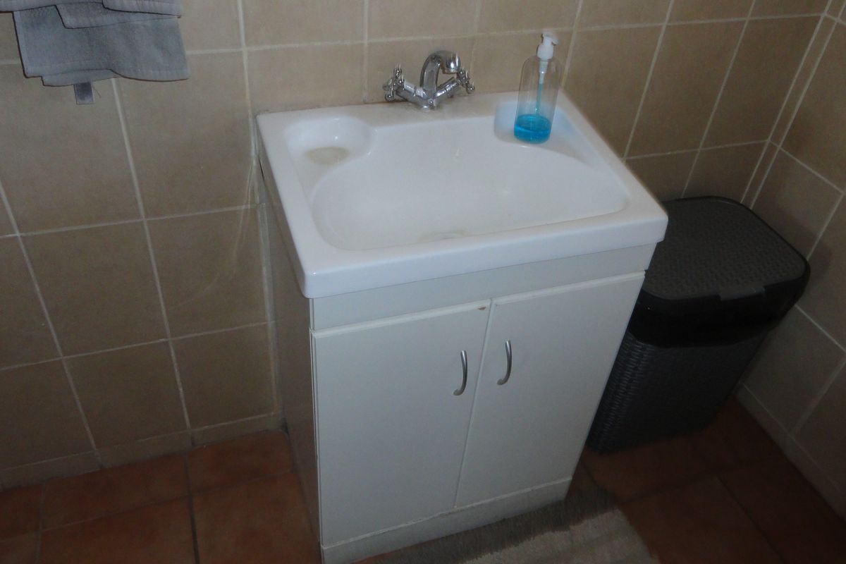 A functional bathroom vanity featuring a white ceramic basin, chrome mixer tap, and tiled wall finishes.