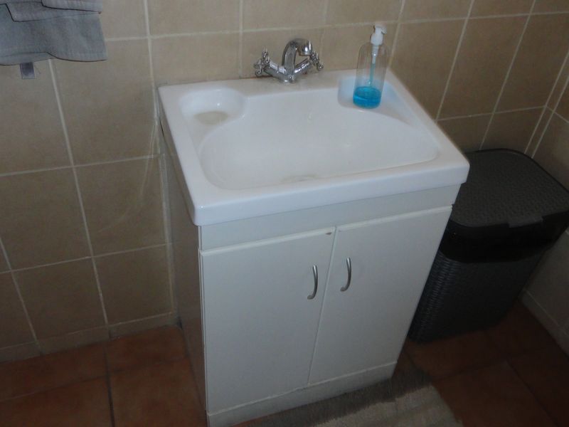 A functional bathroom vanity featuring a white ceramic basin, chrome mixer tap, and tiled wall finishes.