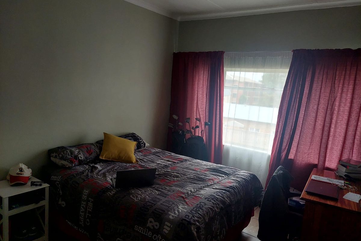 A standard bedroom featuring tiled flooring and a window with curtains, providing a functional living space.