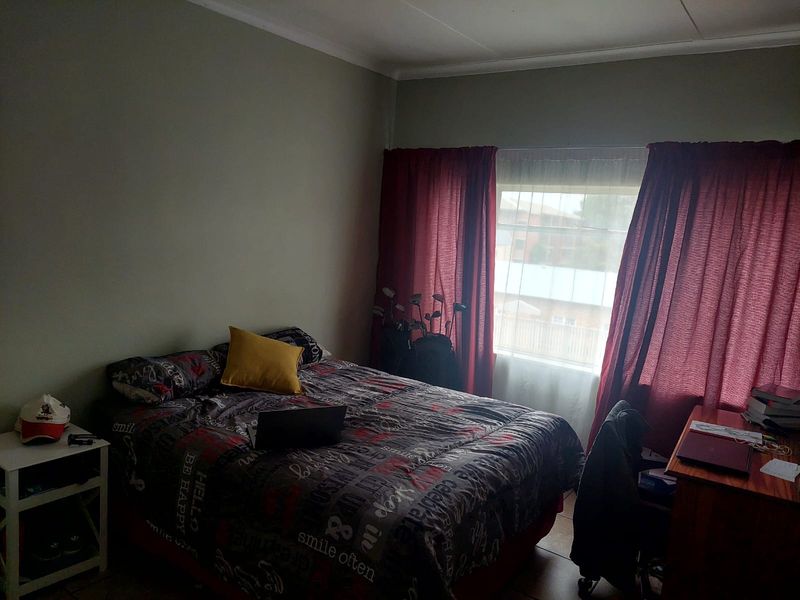 A standard bedroom featuring tiled flooring and a window with curtains, providing a functional living space.