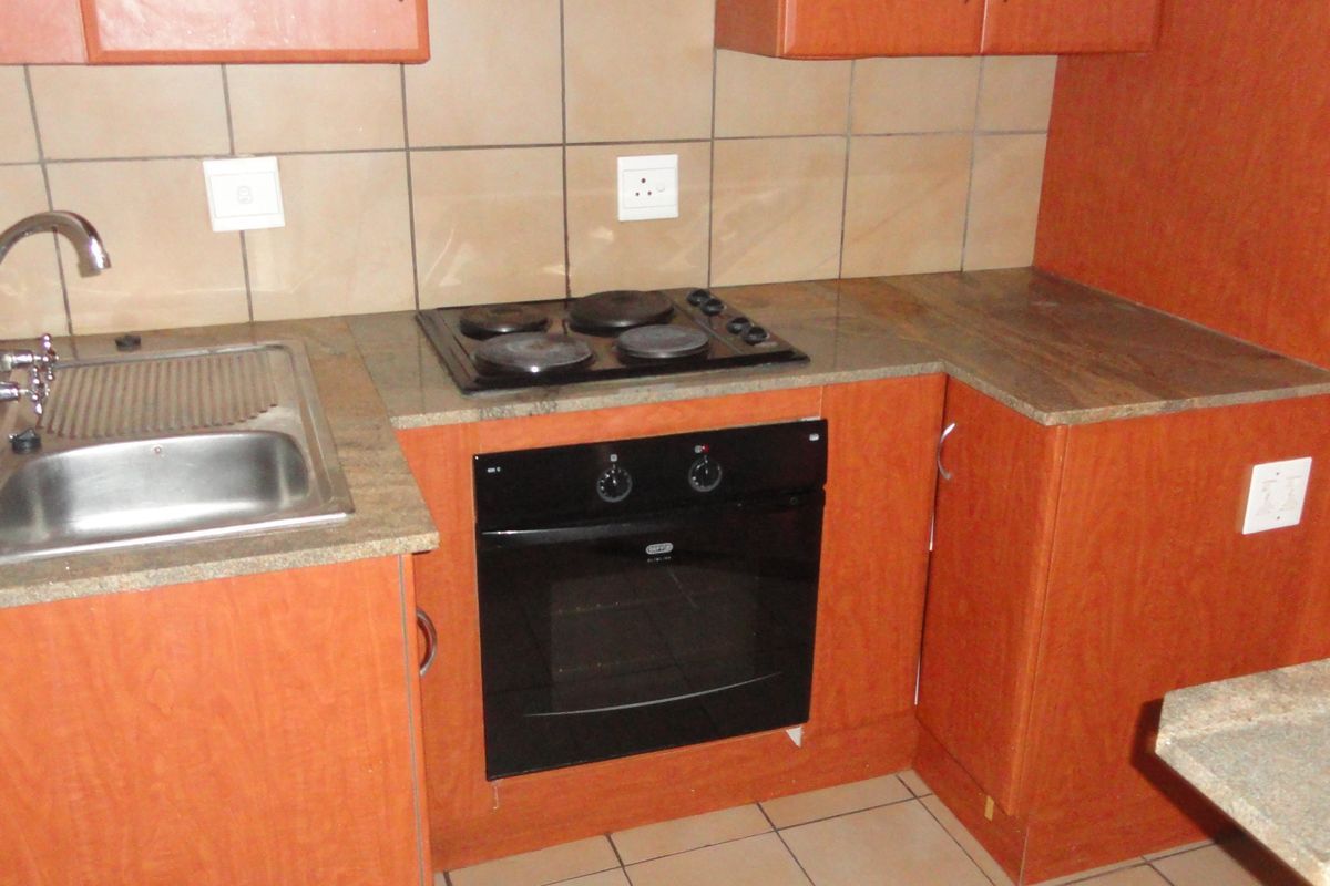 A functional kitchen featuring laminate cabinetry, stone countertops, a built-in oven, and an electric hob with tiled backsplash.