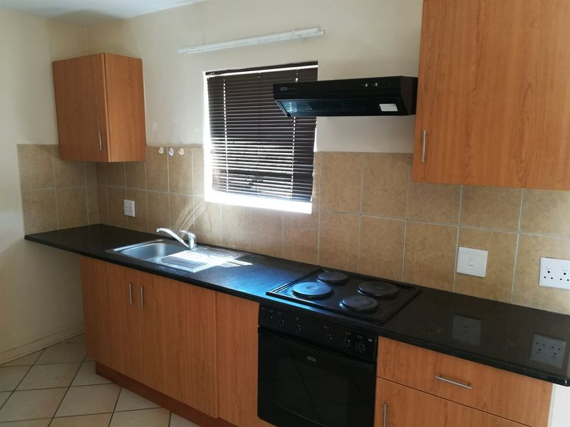 A functional kitchen featuring laminate cabinetry, granite countertops, a built-in oven with hob, and a tiled backsplash.