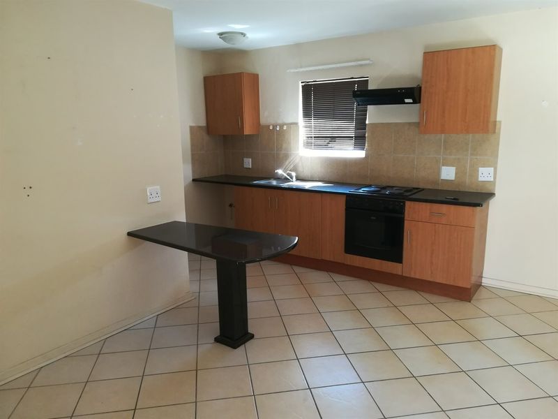 A functional kitchen featuring wood-finish cabinetry, dark countertops, a built-in oven and hob, and a convenient breakfast bar area.