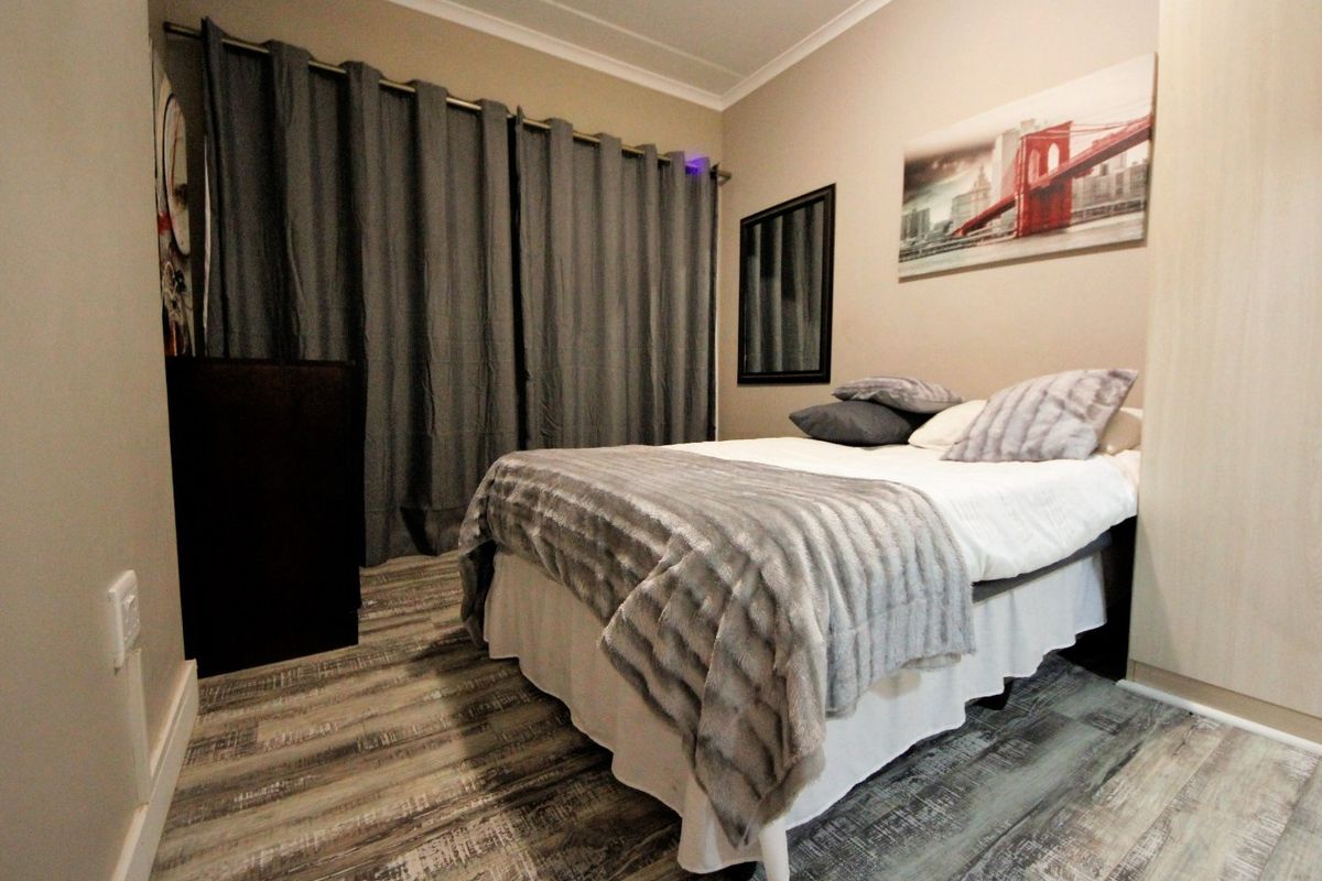 A well-maintained bedroom featuring modern laminate flooring, neutral wall tones, and a built-in wardrobe.