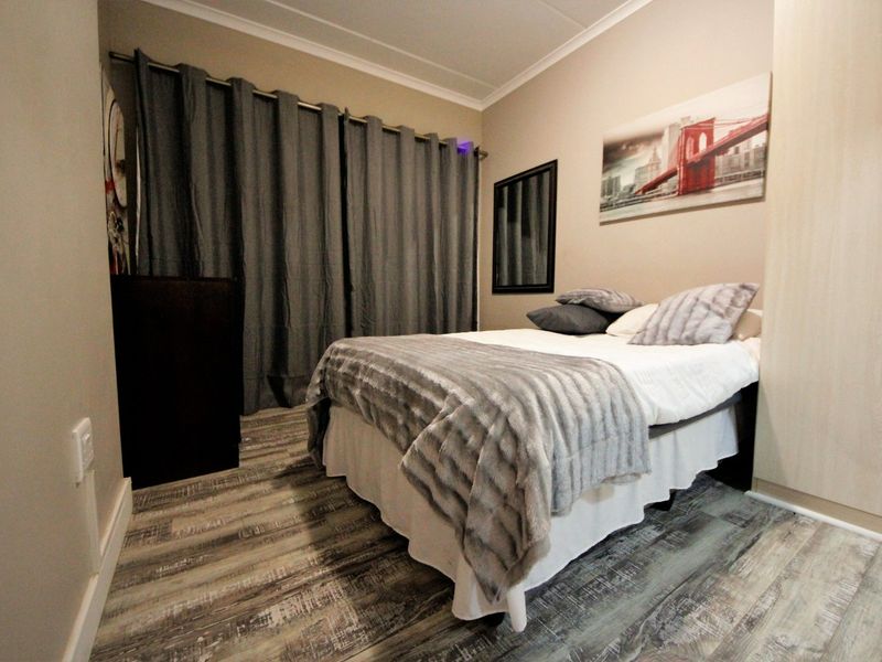 A well-maintained bedroom featuring modern laminate flooring, neutral wall tones, and a built-in wardrobe.