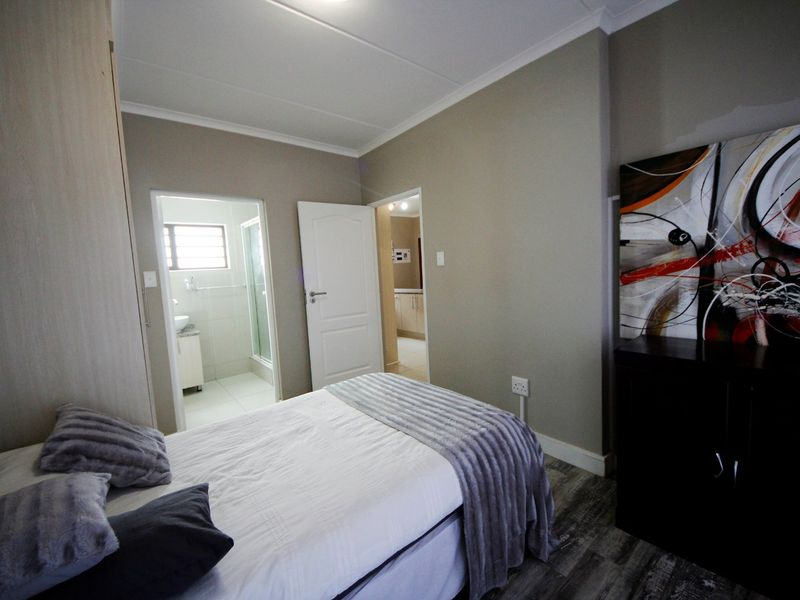 A well-maintained bedroom featuring laminate flooring, built-in cupboards, and direct access to an en-suite bathroom.