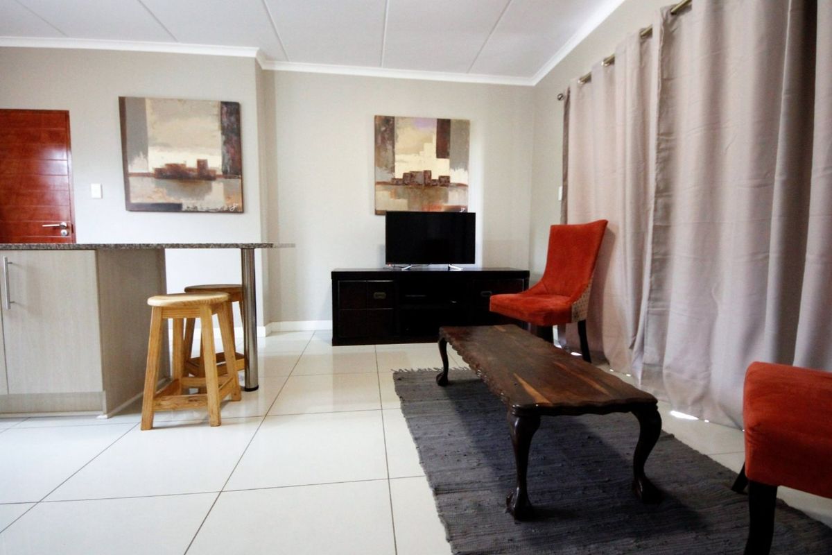 An open-plan living area featuring tiled flooring, a granite breakfast bar, and a sliding door leading to an outdoor space.