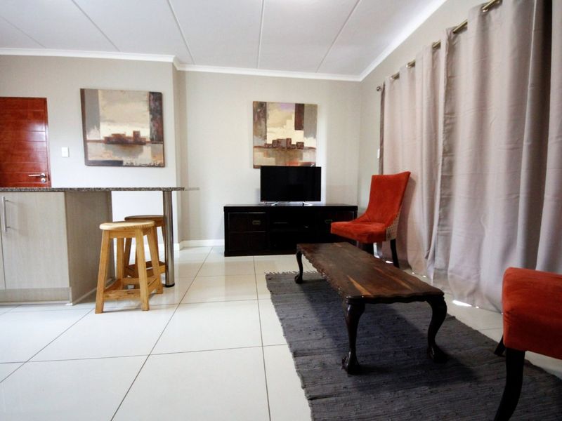 An open-plan living area featuring tiled flooring, a granite breakfast bar, and a sliding door leading to an outdoor space.