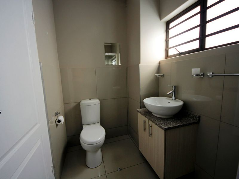 A clean, modern guest bathroom featuring a vessel sink on a granite-topped vanity, tiled walls, and a standard toilet.