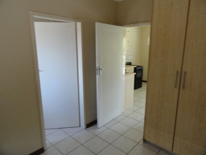 A functional hallway featuring tiled flooring and built-in cupboards, providing access to adjacent rooms within the apartment.