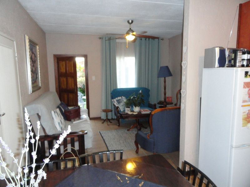 Open plan living area featuring tiled flooring and a ceiling fan, with direct access to an outdoor space.