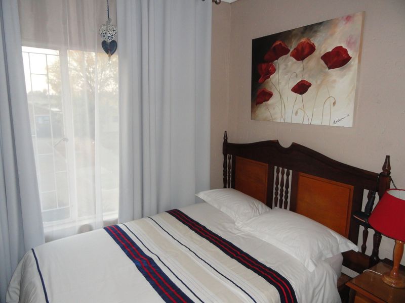 A cozy bedroom featuring a window with security bars and neutral wall finishes, providing a comfortable and functional sleeping space.