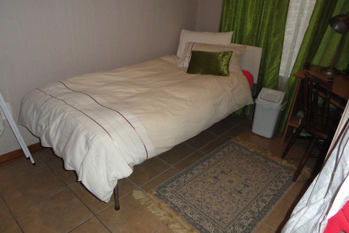 A functional bedroom featuring tiled flooring and neutral wall finishes, suitable for a single bed setup.