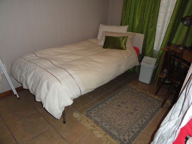 A functional bedroom featuring tiled flooring and neutral wall finishes, suitable for a single bed setup.