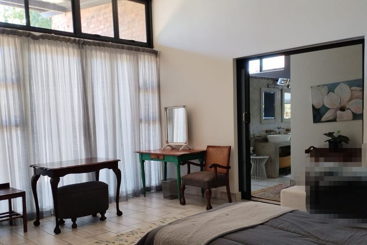 Spacious bedroom featuring tiled flooring, large windows with natural light, and direct access to an en-suite bathroom through a sliding door.