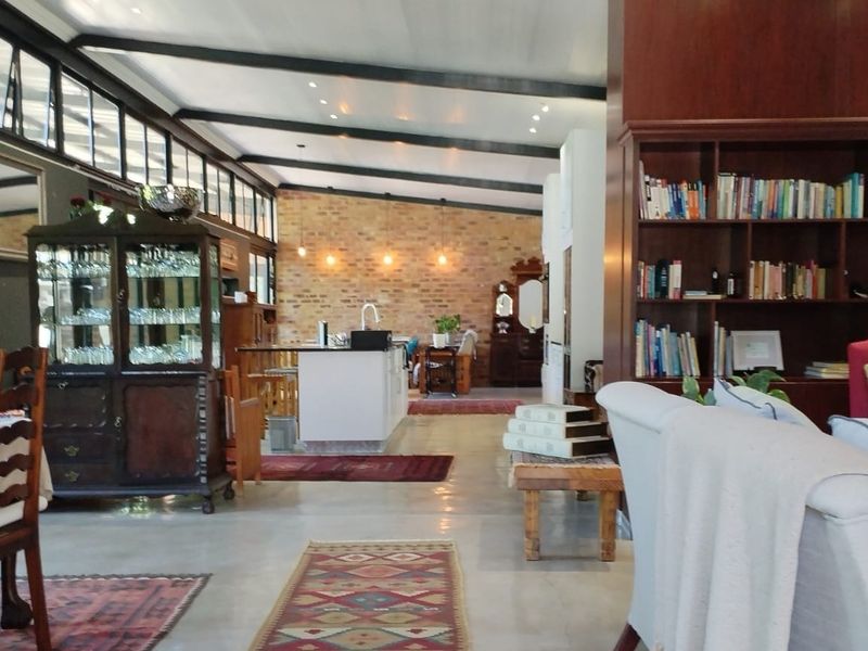 Spacious open-plan living area featuring exposed brick walls, high ceilings with exposed beams, clerestory windows, and a central kitchen island.