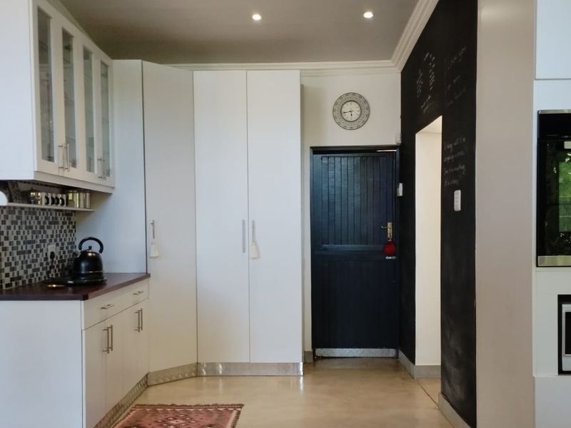 Modern kitchen featuring white cabinetry, built-in oven and microwave, mosaic tile backsplash, and recessed lighting, providing a clean and functional culinary space.
