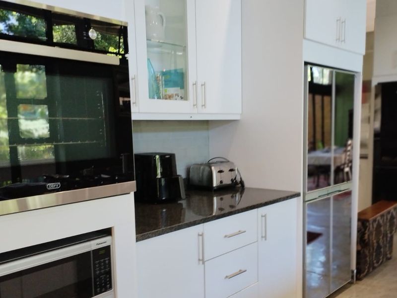 Modern kitchen featuring white cabinetry, granite countertops, and built-in appliances including an oven and microwave, offering a clean and functional cooking space.