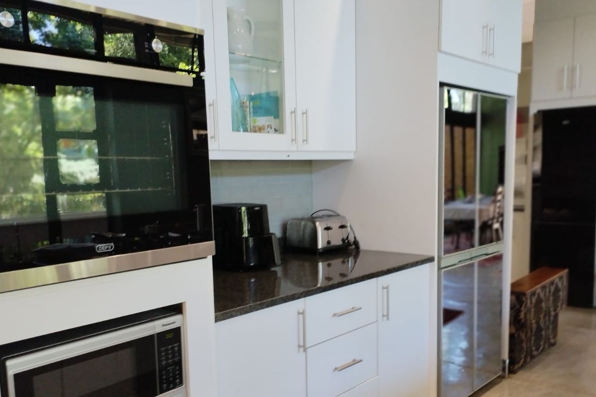Modern kitchen featuring white cabinetry, granite countertops, and built-in appliances including an oven and microwave, offering a clean and functional cooking space.