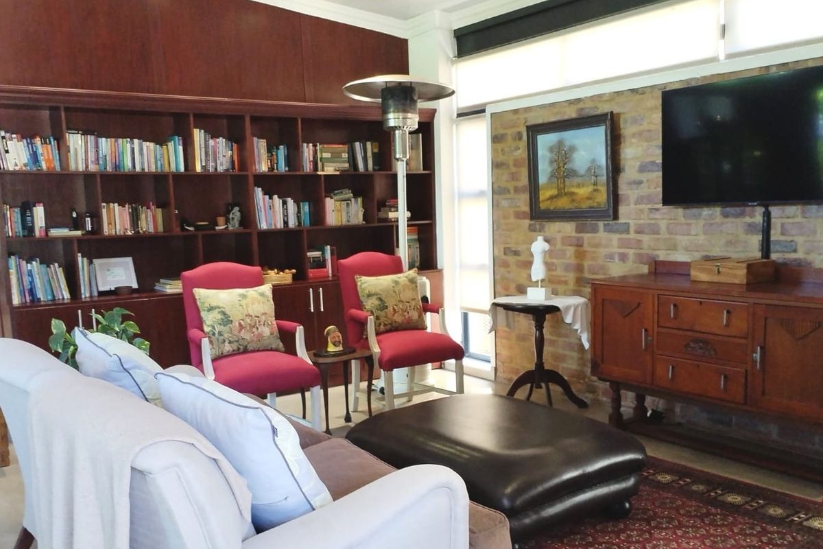 A comfortable living room featuring a large built-in wooden bookshelf and an exposed brick feature wall, creating a warm and inviting atmosphere.