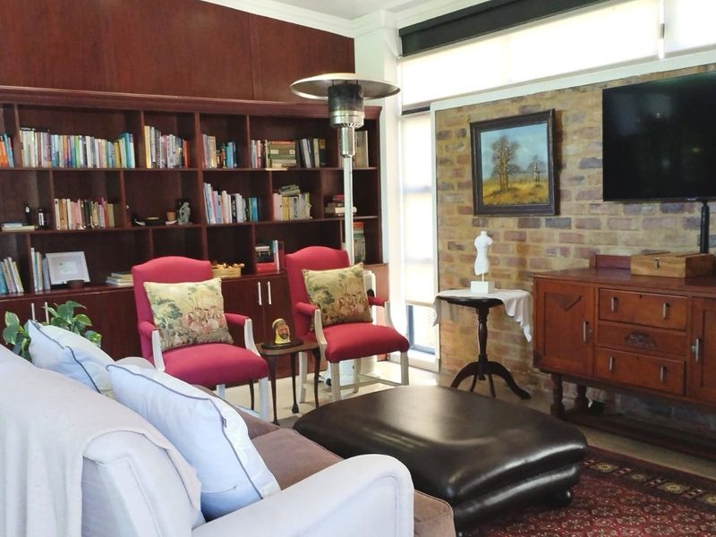 A comfortable living room featuring a large built-in wooden bookshelf and an exposed brick feature wall, creating a warm and inviting atmosphere.