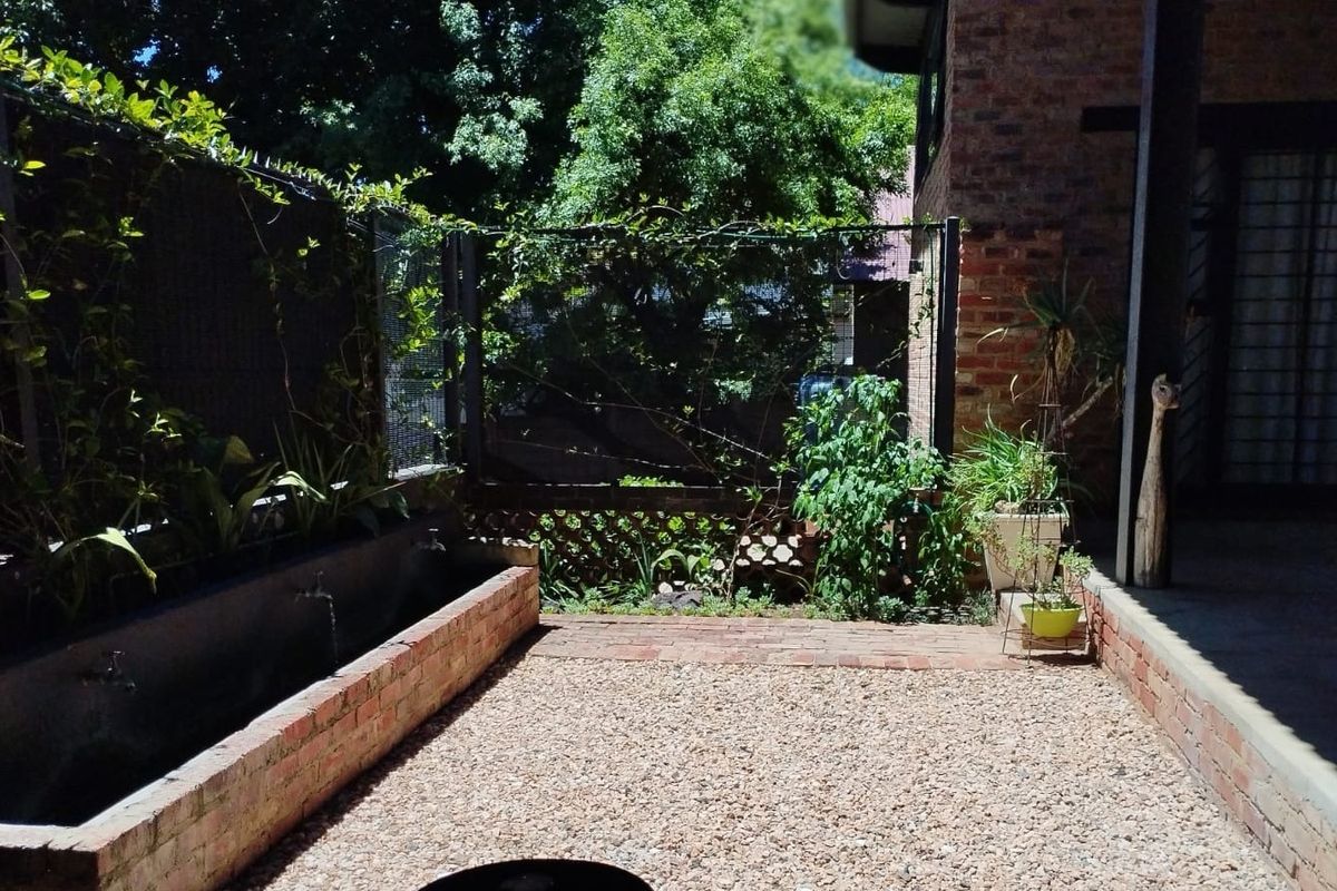 A private rear courtyard featuring a gravel floor, brick retaining walls, and established garden borders, providing a quiet outdoor space.