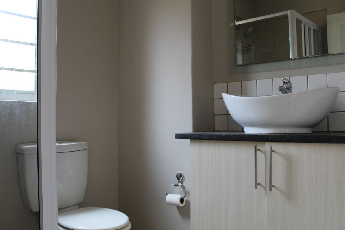 A functional bathroom featuring a modern vessel sink on a vanity cabinet, a toilet, and a wall-mounted mirror.