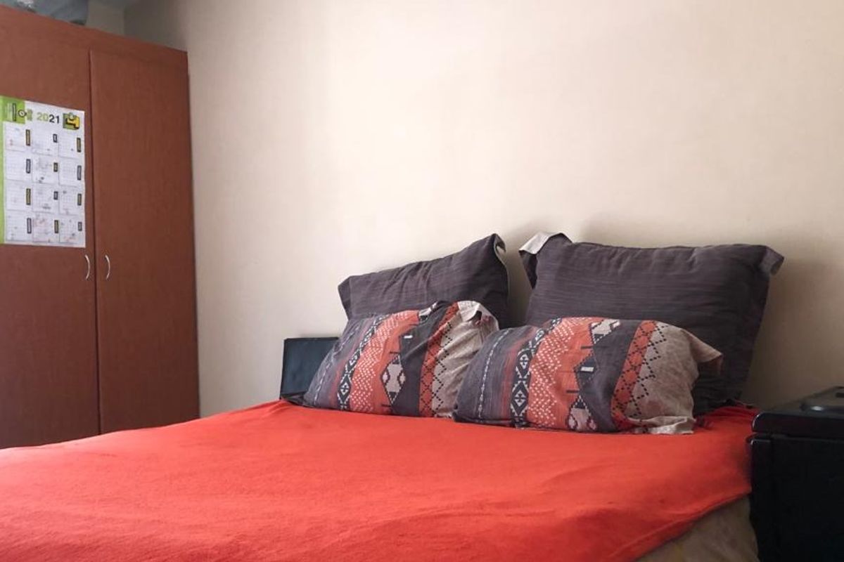 A bedroom featuring a built-in wooden wardrobe and neutral wall finishes.