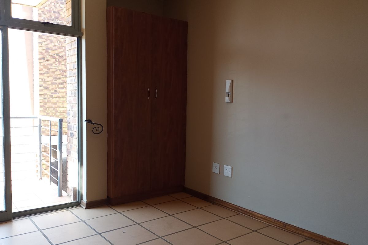 A bedroom featuring tiled flooring, a built-in wooden wardrobe, and a sliding glass door providing access to an outdoor balcony.