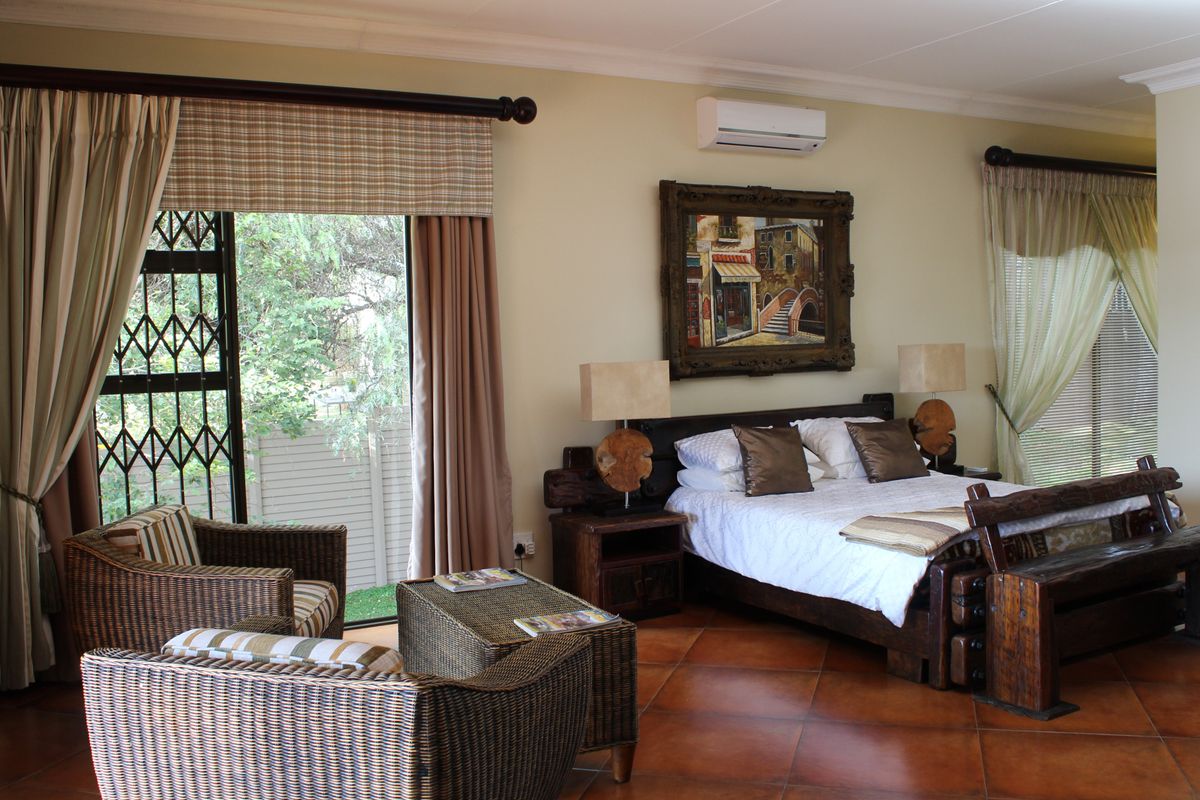 Spacious bedroom featuring tiled flooring, a wall-mounted air conditioning unit, and sliding glass doors with security gates leading to the exterior.