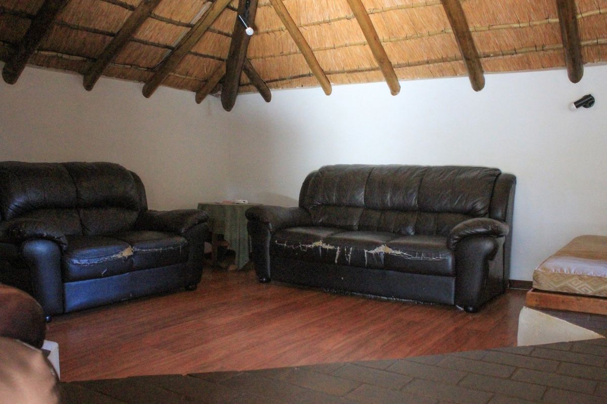 A living room area featuring a high vaulted thatched roof with exposed timber beams and wood-look laminate flooring.