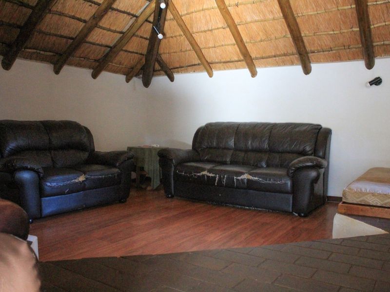A living room area featuring a high vaulted thatched roof with exposed timber beams and wood-look laminate flooring.